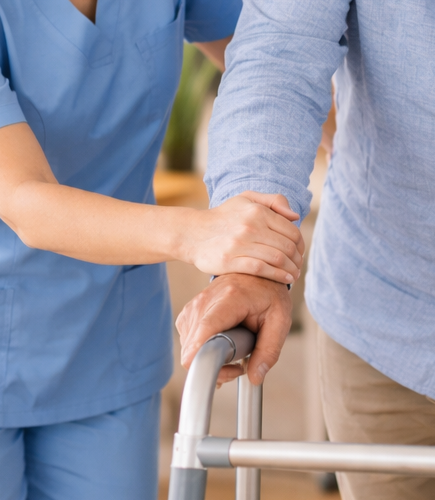 Pflegerin unterstützt beim Gehen
